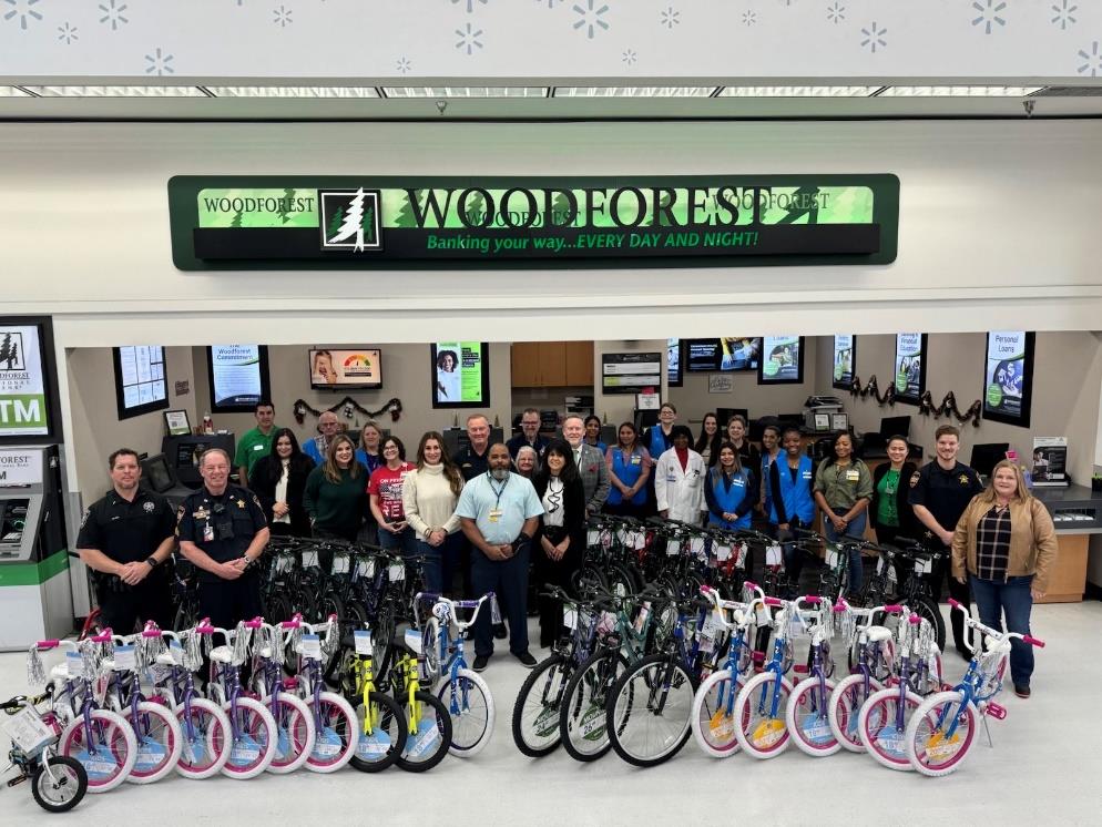 Group photo of volunteers and Woodforest National Bank employees with numerous donated bikes. 